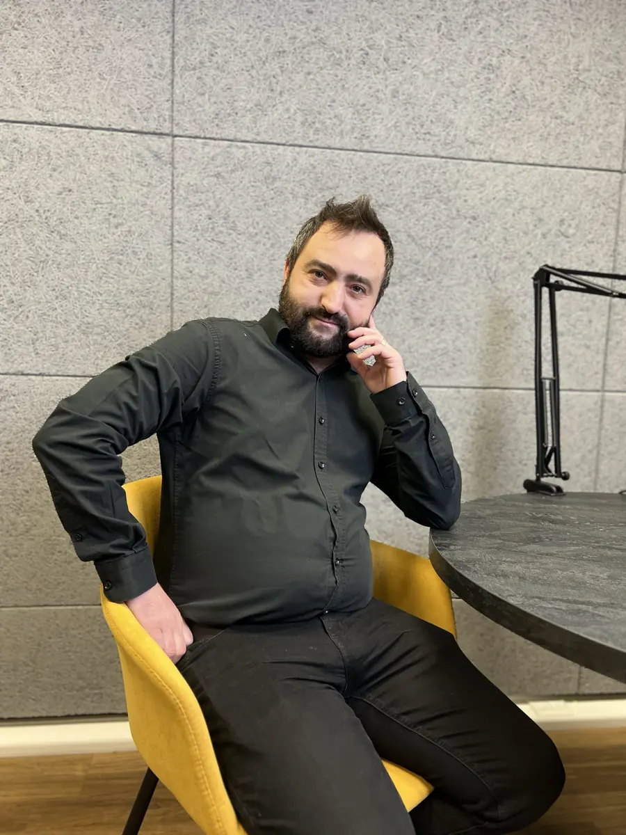 Daniel Pisău așezat pe un fotoliu galben, cu mâna la bărbie, într-un moment de gândire