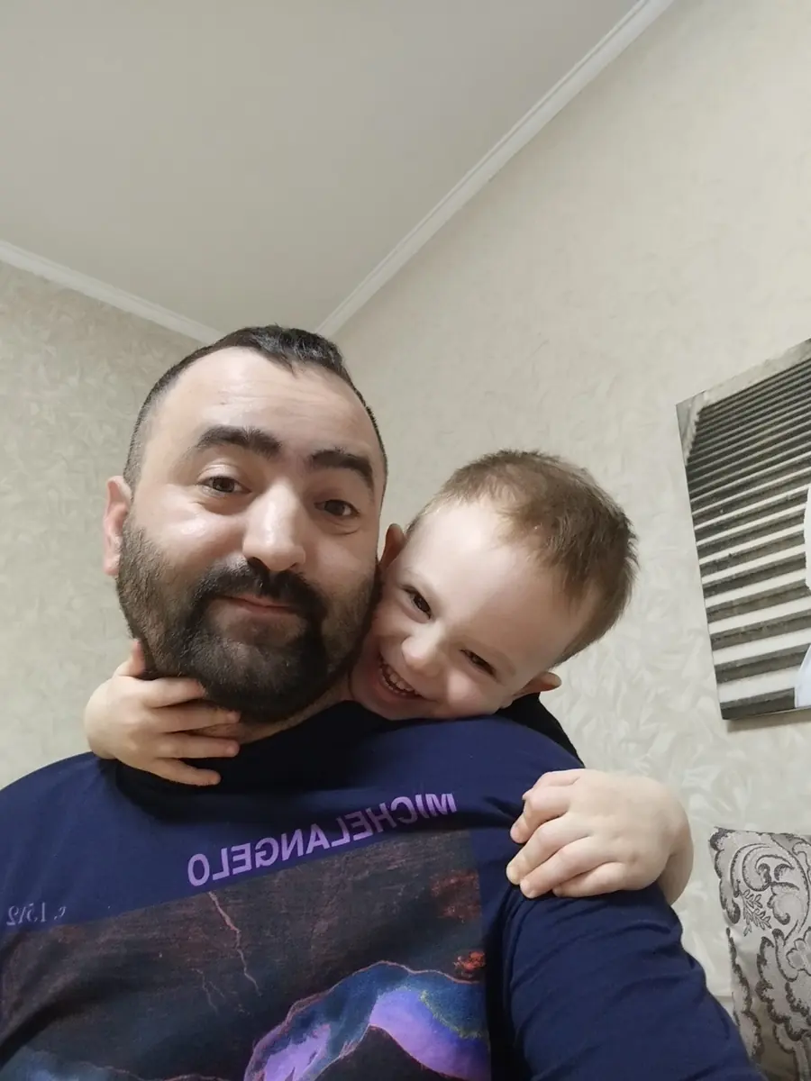 Daniel Pisău ținând în brațe pe fiul său, care îl cuprinde pe după gât
