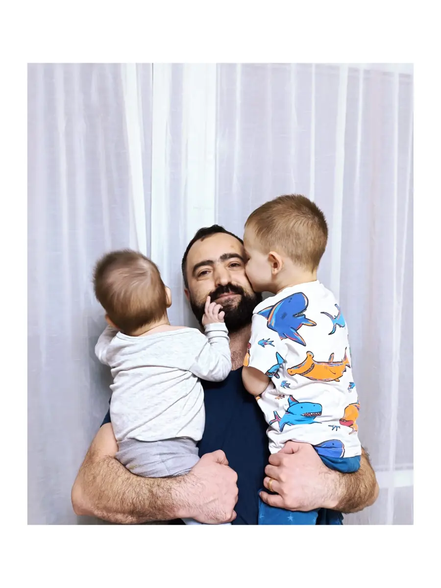Tată ținându-și în brațe cei doi copii, Andrei și Ilie, într-un moment cald de familie